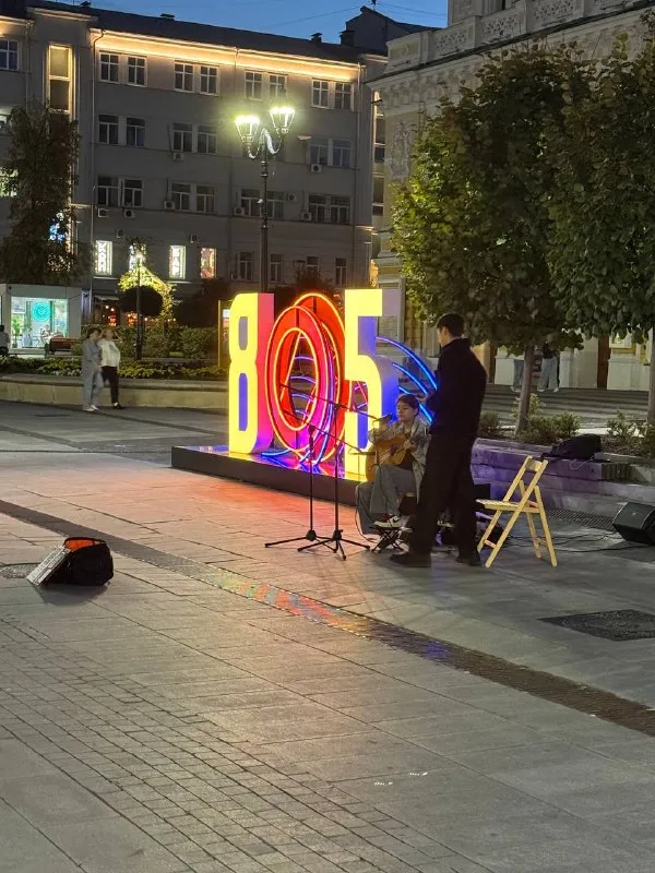 Уличные музыканты у светящейся надписи